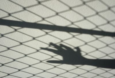 Shadow of chainlink fence on tiled floor