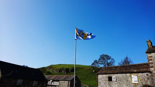 Low angle view of flags against clear blue sky