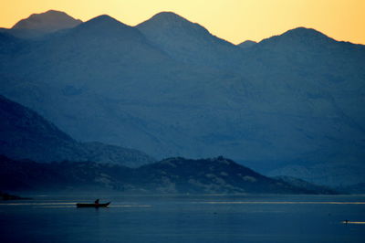 Scenic view of lake by mountains against sky