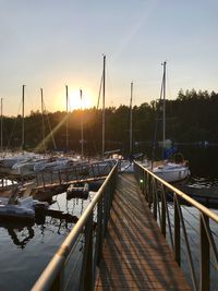 Sailboats moored in harbor at sunset