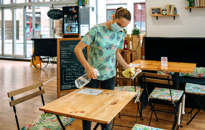 Woman cleaning table at restaurant