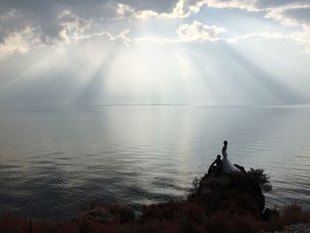 Two people standing on rock next to sea