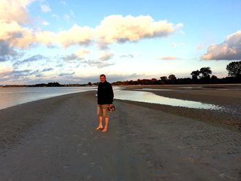 Rear view of man standing on beach against sky