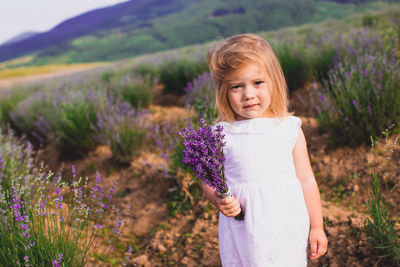 Portrait of woman with purple flowers on field