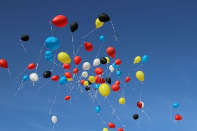 Low angle view of balloons flying against blue sky