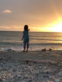 Rear view of man standing on beach during sunset