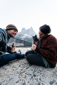 Young couple enjoys a time in wilderness taking selfies laughing and having fun with their gray cat