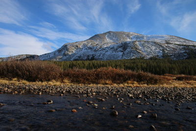 Majestic mountain at riverbank against sky