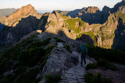 Rear view of people on rock by mountain