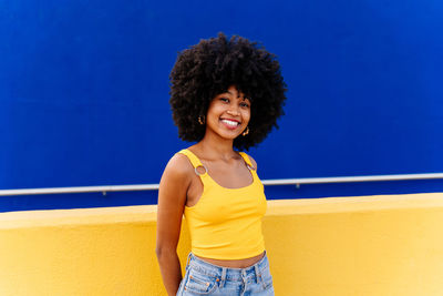 Portrait of young woman standing against wall