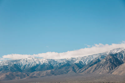 Scenic view of snowcapped mountains against blue sky