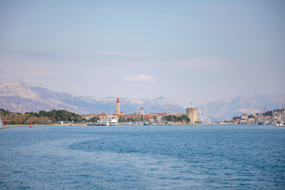 Sea by buildings against sky