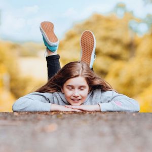 Portrait of smiling girl lying down against sky