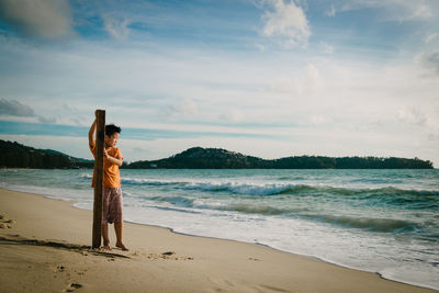 Full length of boy standing on beach against sky