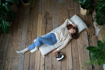 Relaxed millennial woman dreaming after using virtual reality interface, top view