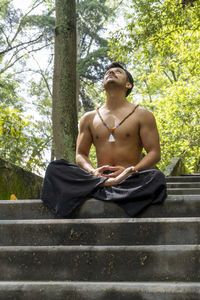 Young man doing meditation on a stairway in a forest, mexico