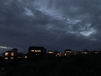 Illuminated city buildings against dramatic sky at night