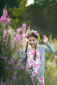 Portrait of smiling woman standing against pink flowering plants