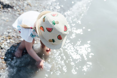 High angle view of girl holding hat in water