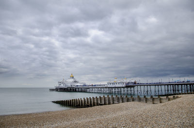 Pier on sea against cloudy sky