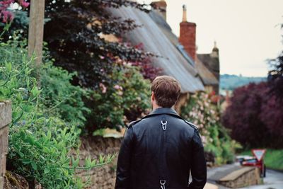 Rear view of man standing by plants against building