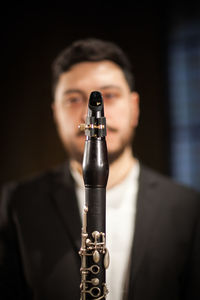 Close-up portrait of man playing trumpet while standing indoors