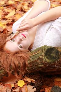 High angle portrait of young woman lying on autumn leaves at park