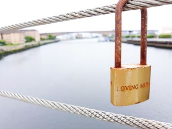 Close-up of padlocks on railing against bridge