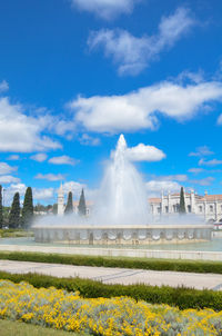 View of fountain on field against cloudy sky