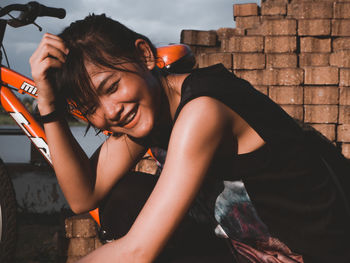 Portrait of young woman sitting against wall