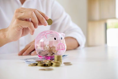 Midsection of businessman inserting coin in piggybank
