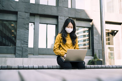 Businesswoman with face mask working using laptop