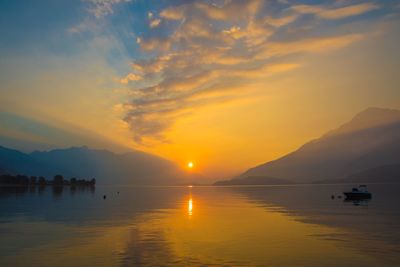 Scenic view of lake against cloudy sky during sunset