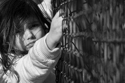 Close-up of cute girl looking through fence