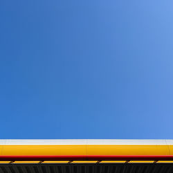 Low angle view of yellow lights against clear blue sky