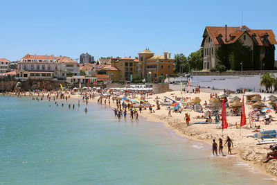 People on beach against buildings in city