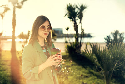 Woman with coffee cup standing in park