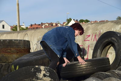 Teenage girl with tires against sky