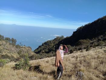 Woman standing on mountain against sky