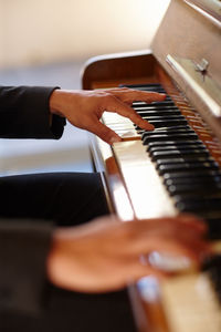 Cropped hand of woman playing piano