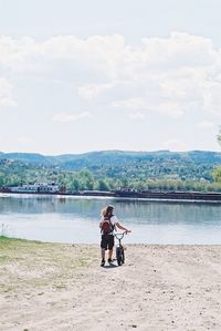 Rear view of man sitting on bench by lake