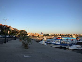 Boats moored at harbor against clear blue sky