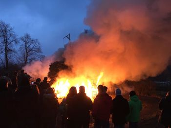Group of people on bonfire against sky at night