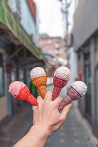 Cropped hand holding ice cream cones in city