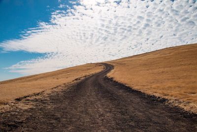 Tire tracks on road against sky