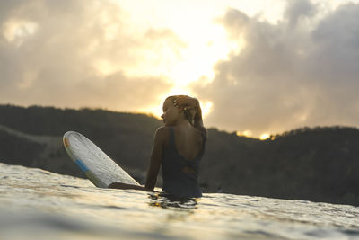 Female surfer in the ocean at sunset