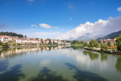 Scenic view of river by buildings against blue sky