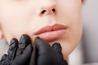 Cropped hands of beautician treating woman lips