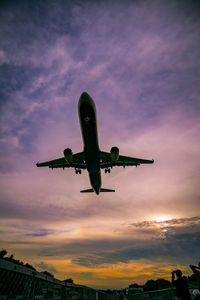 Low angle view of airplane flying in sky during sunset