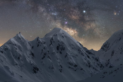 Scenic view of snowcapped mountains against sky at night